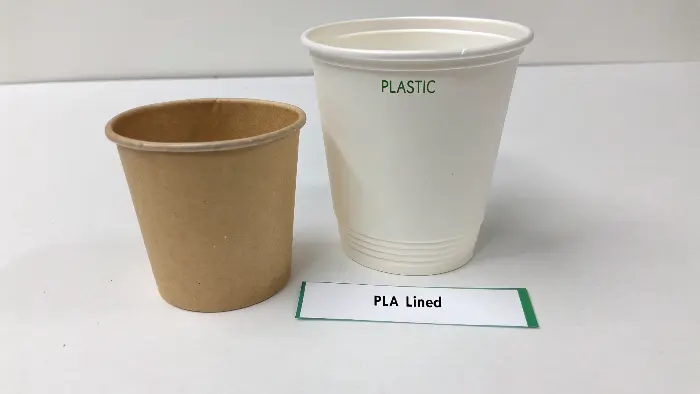 Close-up of a biodegradable coffee cup with cost elements infographic overlay