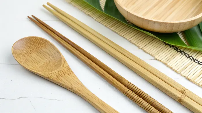 A bamboo cutting board and utensils drying on a clean kitchen rack.