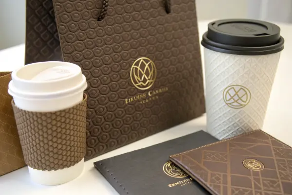 A close-up view of an embossed logo on a kraft paper coffee cup sleeve.
